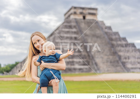 Beautiful tourist woman and her son baby observing the old pyramid and temple of the castle of the Mayan architecture known as Chichen Itza these are the ruins of this ancient pre-columbian 114400291