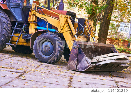 Excavator bulldozer loads old concrete slabs on road repair 114401259
