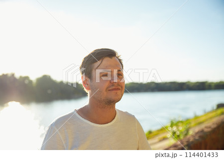 young adult man of 34 years old looking away and dreaming on sunset, male thinking of successful future vision. river embankment waterfront. Positive emotions, leisure activity, relax, rest. lifestyle 114401433
