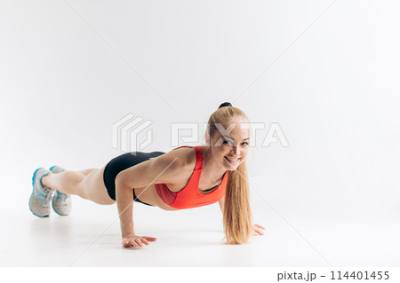 Beautiful slim brunette doing some push ups a the gym 114401455