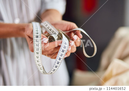 woman's hand holding tailor measuring tape 114401652