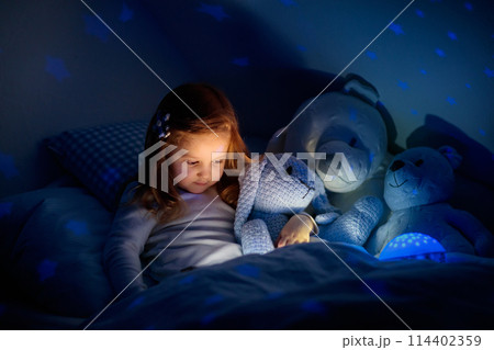 Little girl reading a book in bed Little girl reading a book in bed 114402359