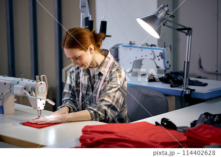Textile cloth factory working process tailoring modern clothes, young woman at work 114402628
