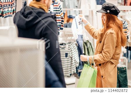 pregnant young woman choosing clothes for baby 114402872
