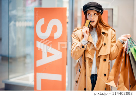 joyous caucasian woman holding discount card in clothes store 114402898