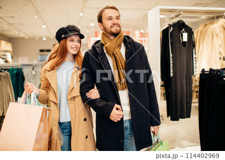 beautiful caucasian couple shopping together in clothes shop 114402969