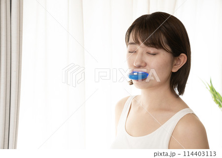 歯のホワイトニングをする女性 114403113