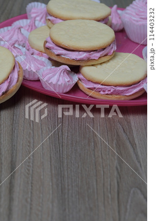 Cooked marshmallow sandwiches. They lie on plate. Next on the plate is a marshmallow of various sizes. 114403232