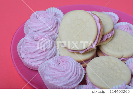 Cooked marshmallow sandwiches. They lie on plate. Next on the plate is a marshmallow of various sizes. 114403260