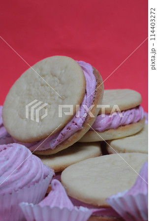 Cooked marshmallow sandwiches. They lie on plate. Next on the plate is a marshmallow of various sizes. 114403272