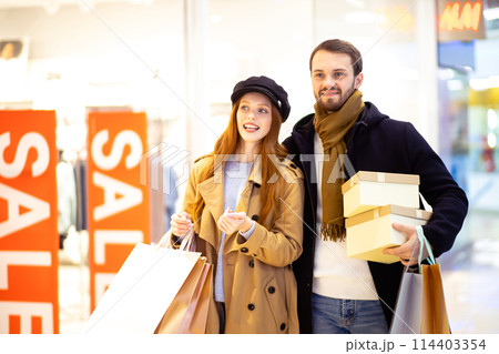 cheerful happy married couple buy gifts for friends in mall 114403354