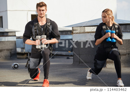 two active athletes are doing lunge exercises with dumbbells two active athletes are doing lunge exercises with dumbbells 114403462