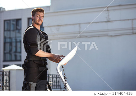 awesome brown-haired male touching the screen of an ems tablet during workout awesome brown-haired male touching the screen of an ems tablet during workout 114404419