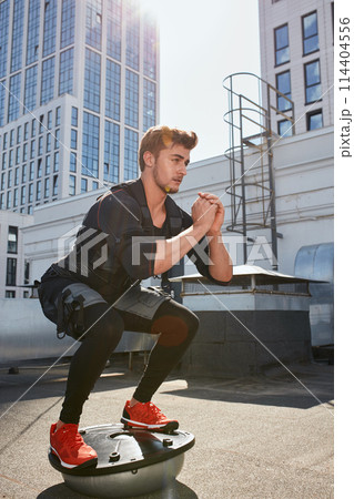 handsome man doing squats on fit ball. muscle stimulation handsome man doing squats on fit ball. muscle stimulation 114404556