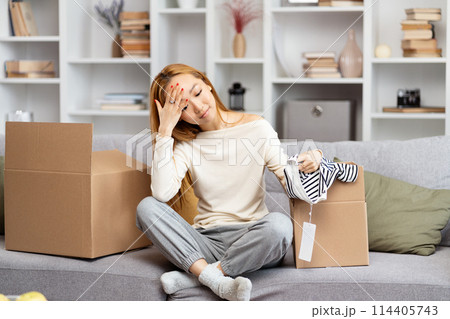 Young Woman Unpacking Boxes In Modern Living Room Young Woman Unpacking Boxes In Modern Living Room 114405743