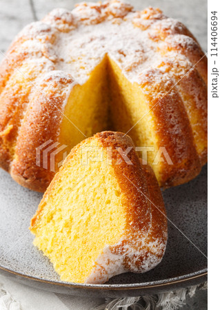 Close-up of Meskouta orange pound cake with powdered sugar on a plate. Vertical 114406694
