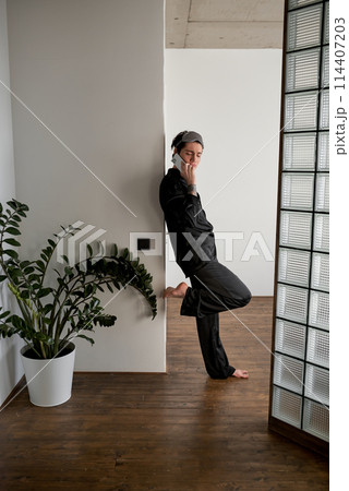 tender romantic man in ashion black shirt and pants chatting on the cell phone 114407203