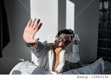 young attractive man hiding from the sunlight young attractive man hiding from the sunlight 114407239