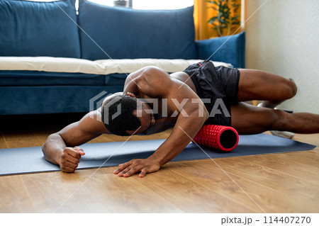 young muscular black man training on floor with sport equipment, at home alone young muscular black man training on floor with sport equipment, at home alone 114407270