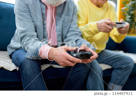 Cropped senior people playing video game console. aged people playing video game battle Cropped senior people playing video game console. aged people playing video game battle 114407411