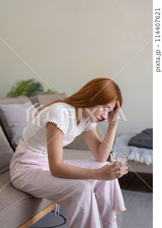 Woman asian frustrated ill sit sofa suffer headache migraine pain have health problem in house living room 114407621