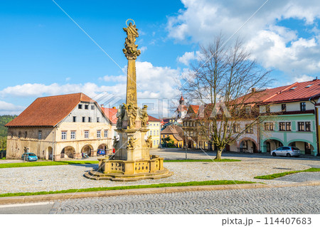 A baroque-style Marian column stands as a centerpiece in Rychorske Square in Zacler, Czech Republic. The square is surrounded by classic European buildings under a bright blue sky. A baroque-style Marian column stands as a centerpiece in Rychorske Square in Zacler, Czech Republic. The square is surrounded by classic European buildings under a bright blue sky. 114407683