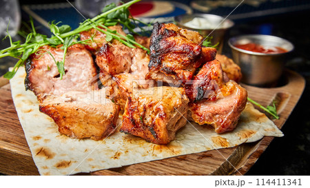 Pork shish kebab on pita bread with two types of sauces 114411341