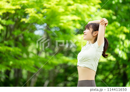 緑の中でストレッチをする笑顔の女性 緑の中でストレッチをする笑顔の女性 114411650