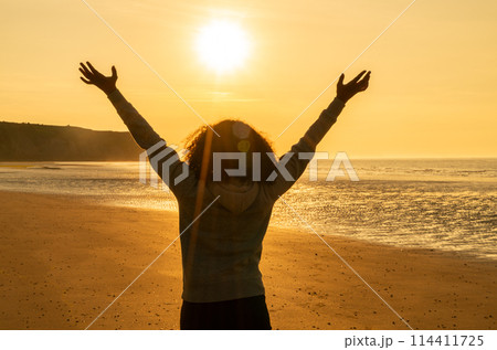Female Woman Girl Arms Raised on an Empty Beach at Sunset Female Woman Girl Arms Raised on an Empty Beach at Sunset 114411725