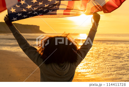 African American Girl Teenager With US Flag Beach at Sunset 114411728
