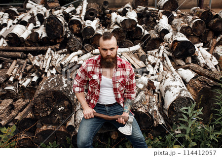 Man sitting on firewoods. Woodcutter with axe resting after work Man sitting on firewoods. Woodcutter with axe resting after work 114412057