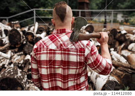 Rear view of lumberjack in forest holding an axe on his shoulder 114412080