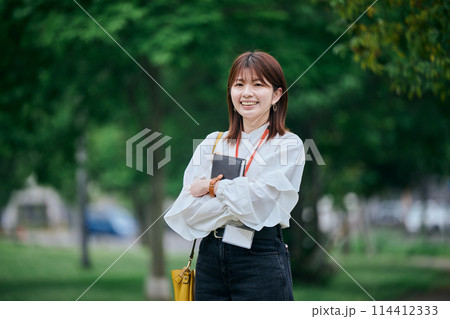 手帳を持って微笑む若い女性 114412333