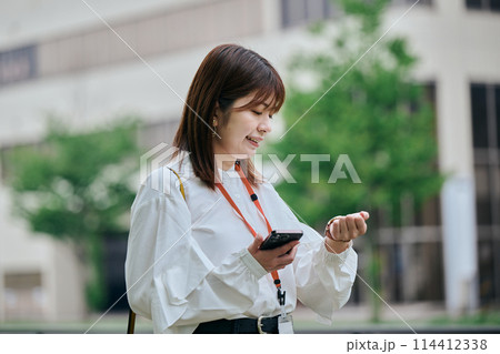 時計を見ながら歩く若い女性 時計を見ながら歩く若い女性 114412338