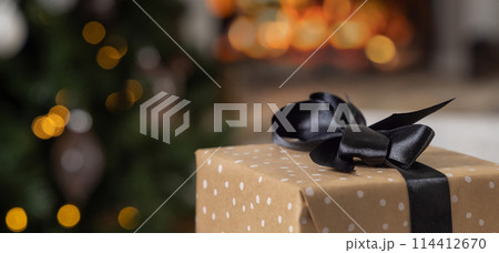 Christmas gifts with black bows on background of burning fireplace and christmas tree Christmas gifts with black bows on background of burning fireplace and christmas tree 114412670