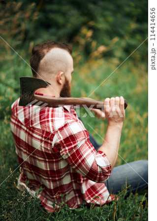 Lumberjack sitting in forest resting after hard work 114414656