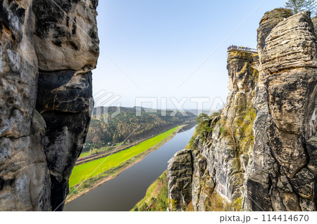 Overlooking the serene Elbe River from the iconic Bastei rock formation in Saxon Switzerland National Park, Germany, on a clear spring day. Overlooking the serene Elbe River from the iconic Bastei rock formation in Saxon Switzerland National Park, Germany, on a clear spring day. 114414670