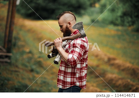 Bearded Man with firewoods and with axe on shoulder Bearded Man with firewoods and with axe on shoulder 114414671