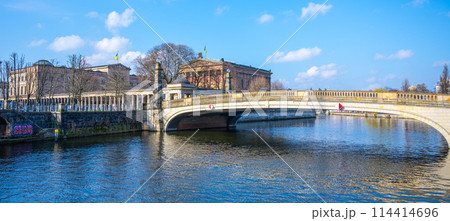 Friedrichs Bridge spans a river in Berlin under a clear blue sky, with nearby historical buildings of Museum Island visible. Berlin, Germany 114414696