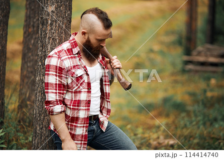 bearded lumberjack worker standing in forest with axe 114414740
