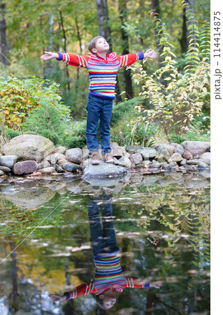 Child on an autumn walk. Upright boy in a warm sweater by the autumn lake. Child on an autumn walk. Upright boy in a warm sweater by the autumn lake. 114414875