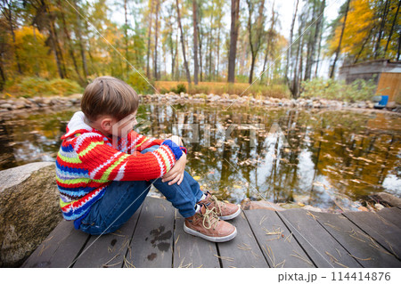 Child on an autumn walk. The boy walks on a background of autumn nature. Child on an autumn walk. The boy walks on a background of autumn nature. 114414876