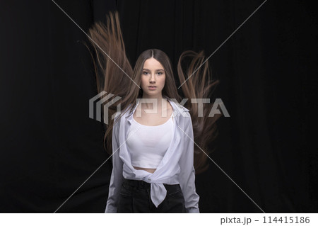 Beautiful brunette with long flying hair on a dark background. Beautiful brunette with long flying hair on a dark background. 114415186