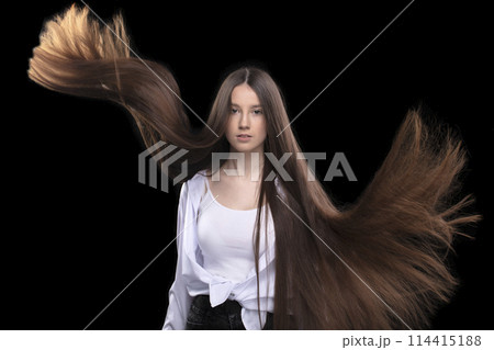 Beautiful brunette with long flying hair on a dark background. Beautiful brunette with long flying hair on a dark background. 114415188