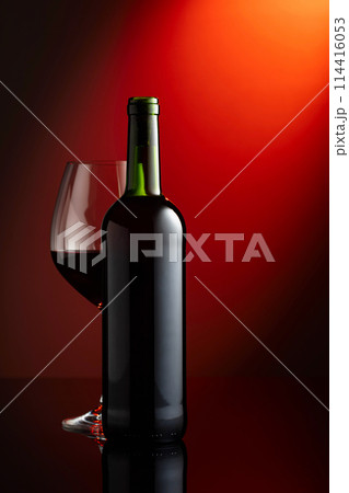 Glass and bottle of red wine on a red background. Glass and bottle of red wine on a red background. 114416053