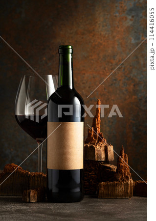 Glass and bottle of red wine with pieces of old wood on a rusty background. Glass and bottle of red wine with pieces of old wood on a rusty background. 114416055
