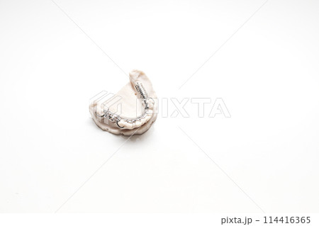 Isolated Metal Frame Lower Partial Denture On Die Stone, Plaster Cast Mold Of Lower Jaws, Cobalt Chrome Dental Plate, Flat Lay Mockup 3D Printed Bridge On White Background. Copy Space. Horizontal. Isolated Metal Frame Lower Partial Denture On Die Stone, Plaster Cast Mold Of Lower Jaws, Cobalt Chrome Dental Plate, Flat Lay Mockup 3D Printed Bridge On White Background. Copy Space. Horizontal. 114416365