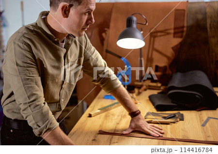 pensive thoughtful craftsman working with piece of leather in workshop pensive thoughtful craftsman working with piece of leather in workshop 114416784