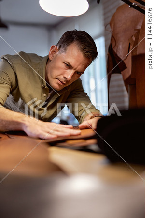 serious man concentrated on selecting leather for sewing bag serious man concentrated on selecting leather for sewing bag 114416826