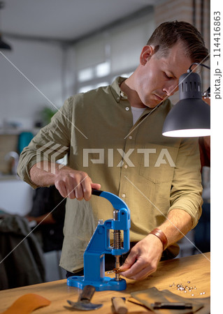 handsome guy in grey shirt pressing, holding the lever on the press machine handsome guy in grey shirt pressing, holding the lever on the press machine 114416863